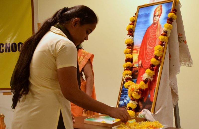 Student paying floral tributes to the portrait of Swami Vivekanand.